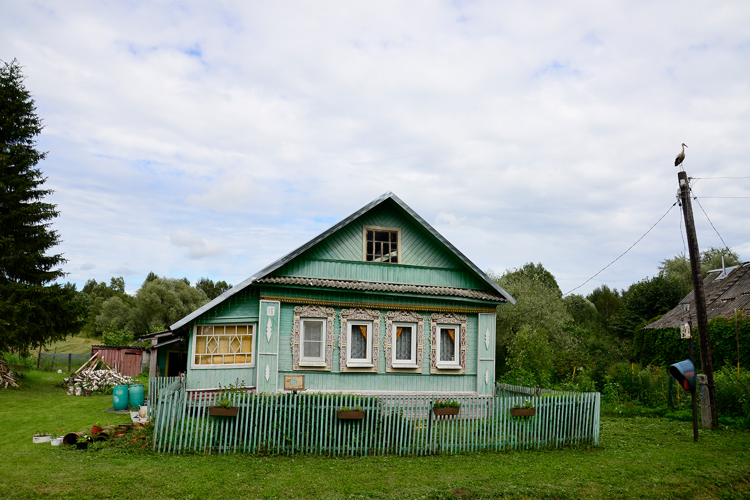 Справа от дома телефон, и по нему можно позвонить бесплатно на городские номера. А на столбе — аист