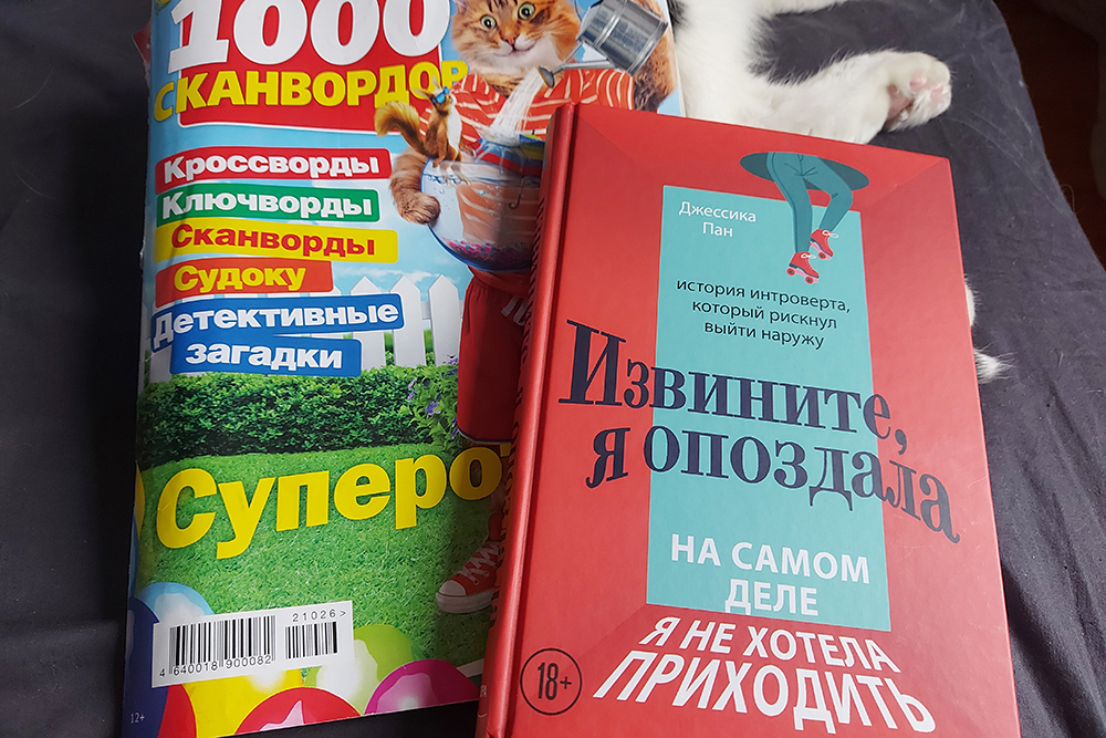 Мои сканворды-кроссворды и прочитанная книга. Под ними немного видно котика