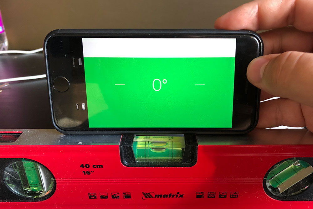 Сверху — уровень на Айфоне. Я приставил его к столешнице и вижу, что она не наклонена по отношению к земле — угол 0°. Снизу — строительный уровень. Когда овальный пузырек четко между двумя линиями — наклона нет
