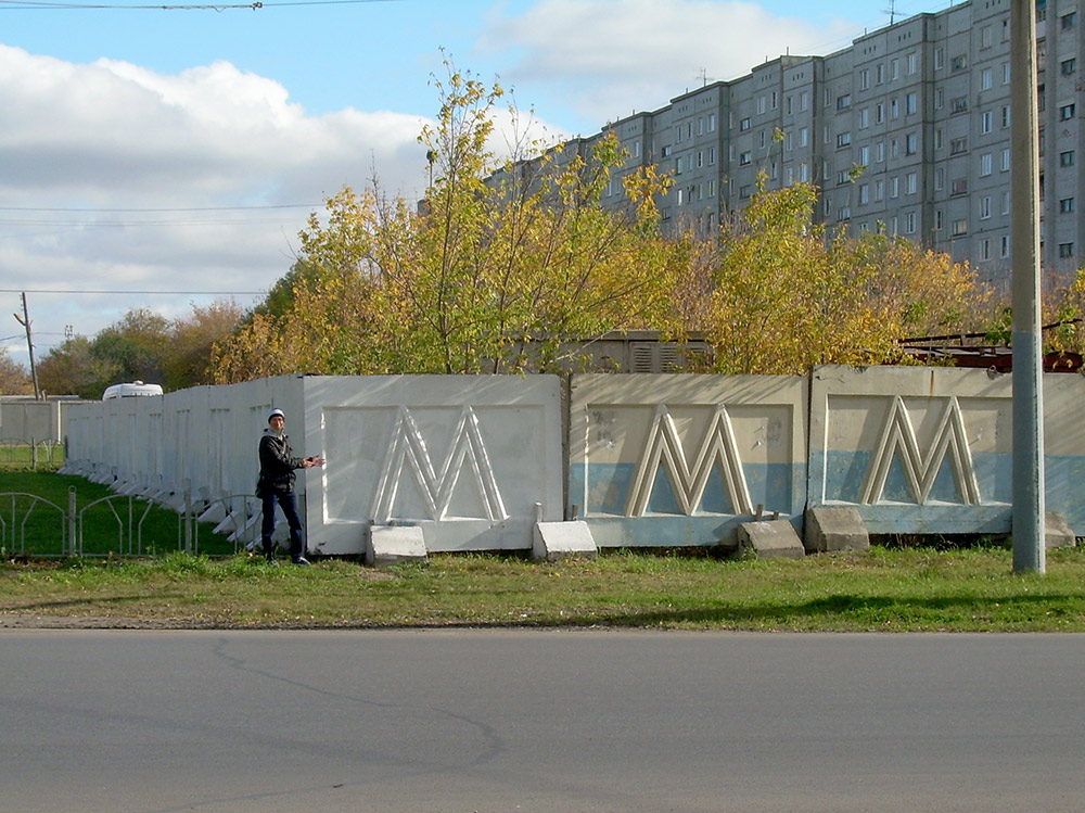 Этот забор поставили возле моего дома 26 лет назад, когда начали строить омское метро. Тогда я ходил в начальную школу и думал: «Ждать метро придется долго. Наверное, я уже школу к тому времени буду заканчивать». За годы стройки такие заборы с буквой «М» ставили и убирали в разных частях города, директор компании-подрядчика отсидел и вышел, причем по другому делу. В этом году правительство Омской области решило прекратить строительство — забор начали сносить