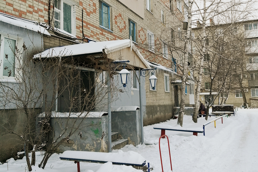 Дом, в котором расположена квартира. Вход в подъезд украшен фонарями, а на козырьке — резьба