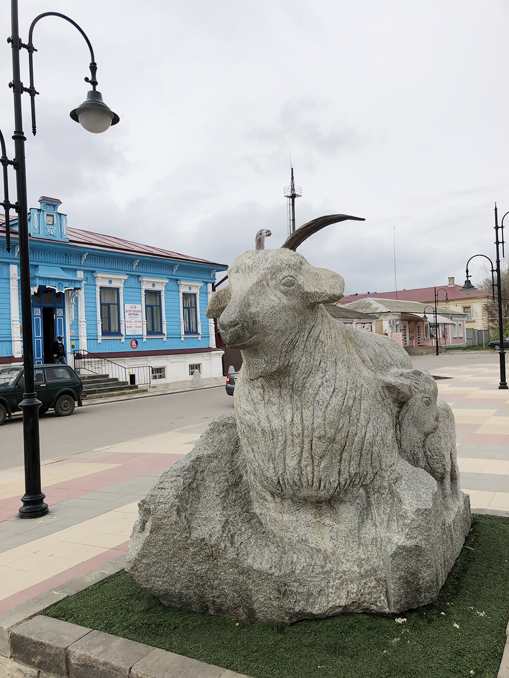 Памятник изготовили из серого гранита. На фоне — здание центральной аптеки