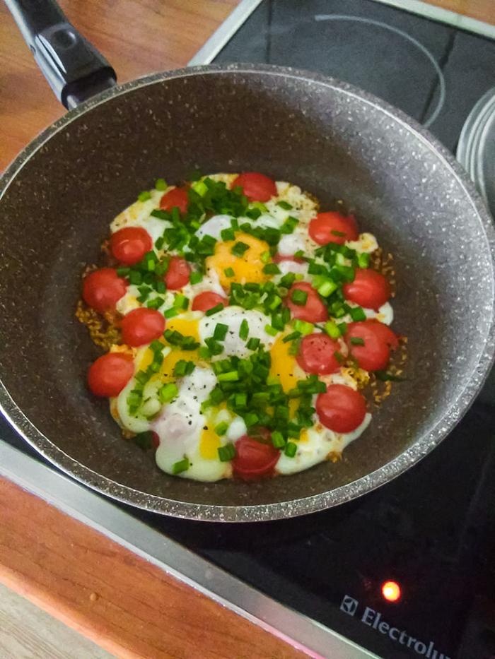 Яичница на топленом масле с зеленым луком, помидорами и черным перцем